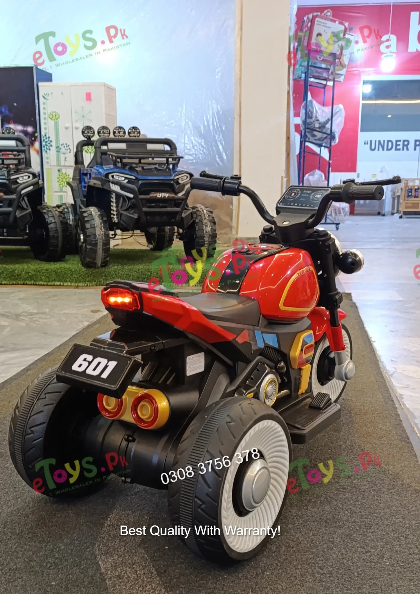 Rear view of kids electric motorcycle trike Model 601 showing dual rear wheels, LED taillights, and gold exhaust details
